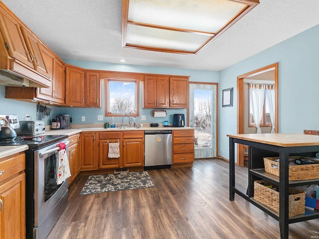 kitchen featuring dark wood-style flooring, stainless steel appliances, a textured ceiling, light countertops, and a sink