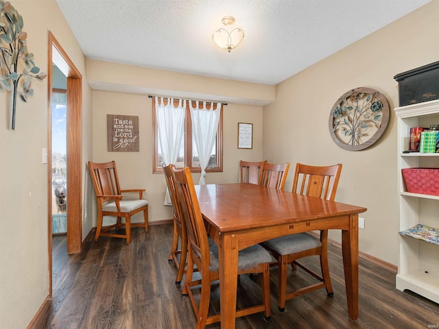 dining area featuring a textured ceiling, dark wood-style flooring, and baseboards