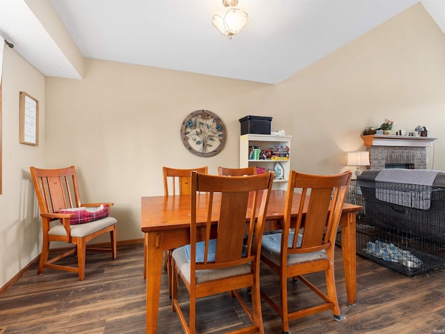 dining space featuring a fireplace, baseboards, and wood finished floors