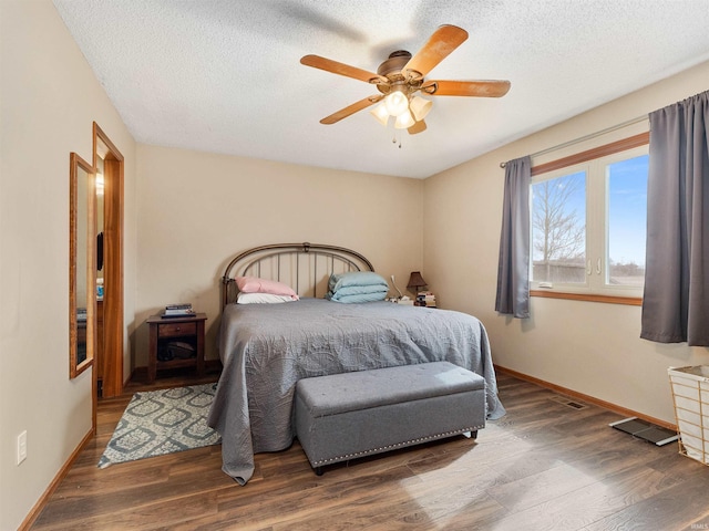 bedroom featuring ceiling fan, a textured ceiling, baseboards, and wood finished floors