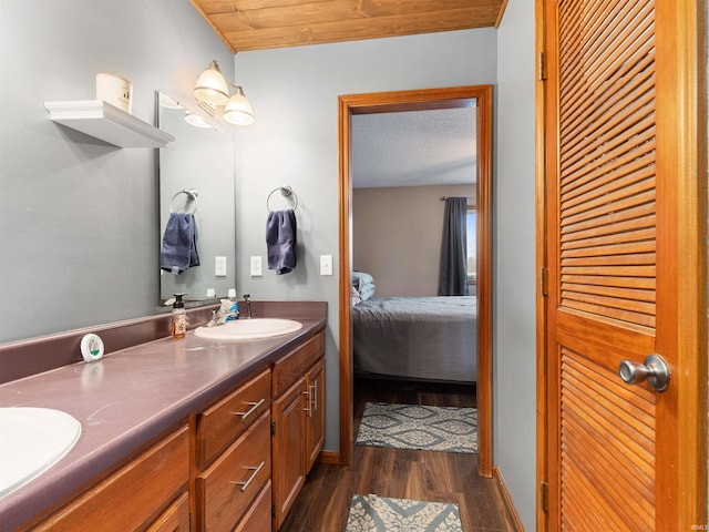 bathroom featuring double vanity, wood finished floors, a sink, and connected bathroom