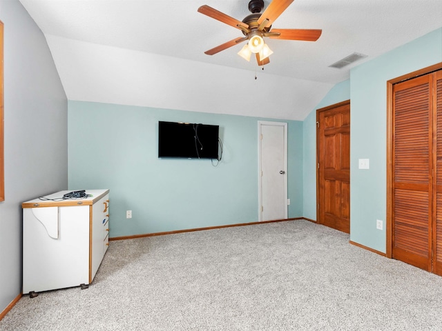 interior space featuring baseboards, visible vents, light colored carpet, lofted ceiling, and a closet