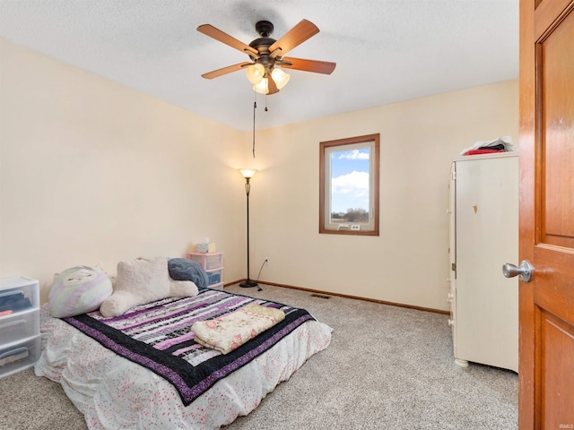 bedroom with a textured ceiling, light carpet, visible vents, a ceiling fan, and baseboards