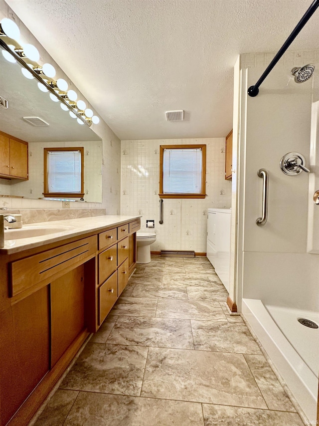 full bathroom featuring visible vents, toilet, a shower stall, vanity, and a textured ceiling