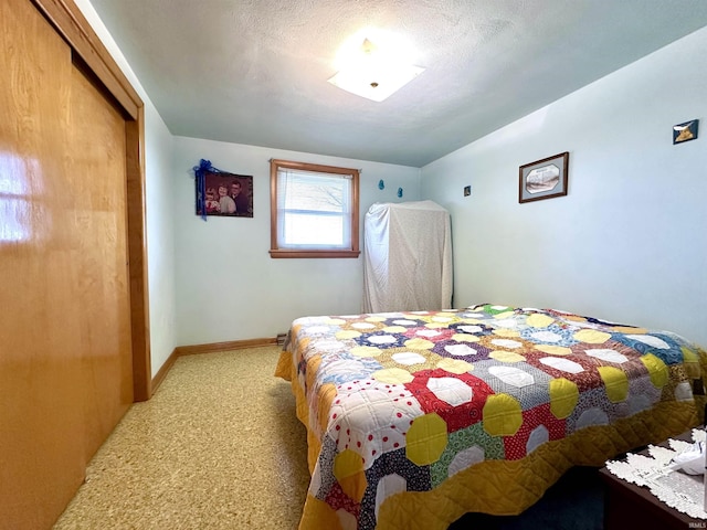 bedroom with a textured ceiling, a closet, light colored carpet, and baseboards