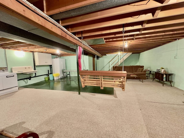 unfinished basement with concrete block wall, a sink, stairs, freestanding refrigerator, and washer / dryer