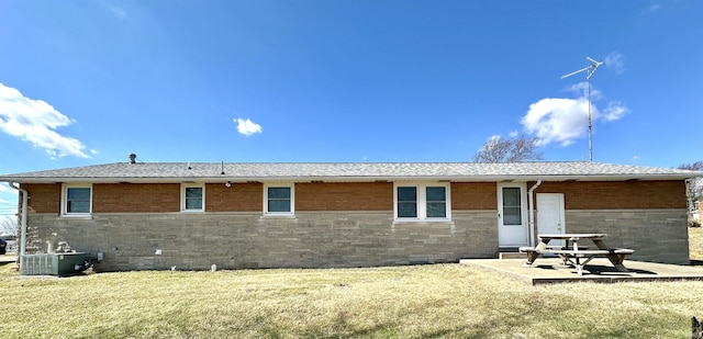 back of property with a lawn, central AC unit, a patio, and brick siding