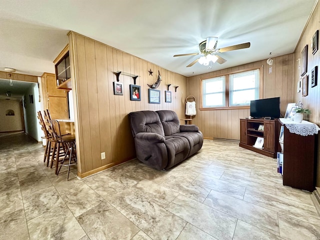 living area with ceiling fan and baseboards