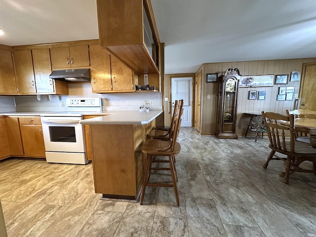 kitchen featuring under cabinet range hood, brown cabinetry, white range with electric cooktop, and light countertops