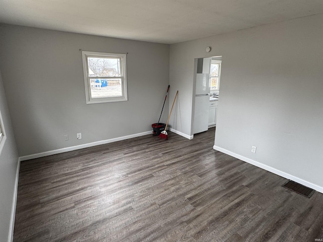 unfurnished room featuring visible vents, dark wood finished floors, and baseboards