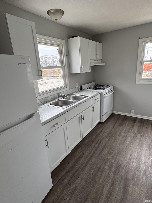 kitchen with white appliances, dark wood-style floors, light countertops, under cabinet range hood, and a sink