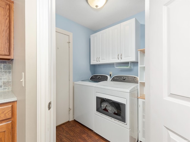 laundry room featuring dark wood-style flooring, washing machine and dryer, and cabinet space