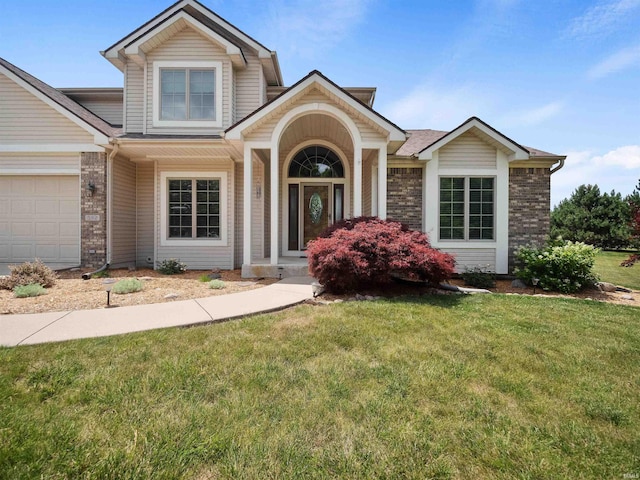 view of front of house with a garage, a front yard, and brick siding