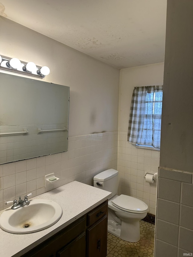 bathroom with tile patterned flooring, vanity, toilet, and tile walls