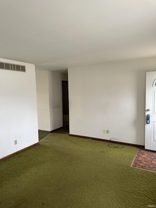 carpeted empty room featuring baseboards and visible vents