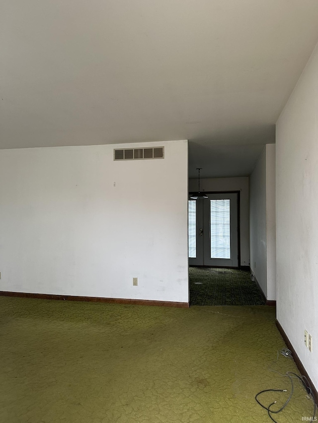 carpeted spare room featuring baseboards, visible vents, and french doors