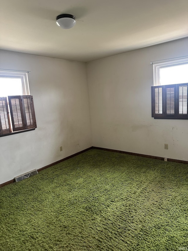 carpeted empty room with a healthy amount of sunlight, visible vents, and baseboards