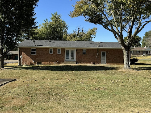 back of property featuring french doors, brick siding, and a lawn