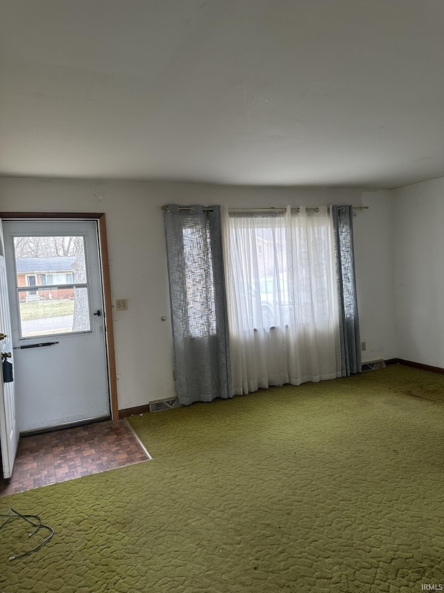 foyer entrance featuring visible vents, carpet flooring, and a wealth of natural light