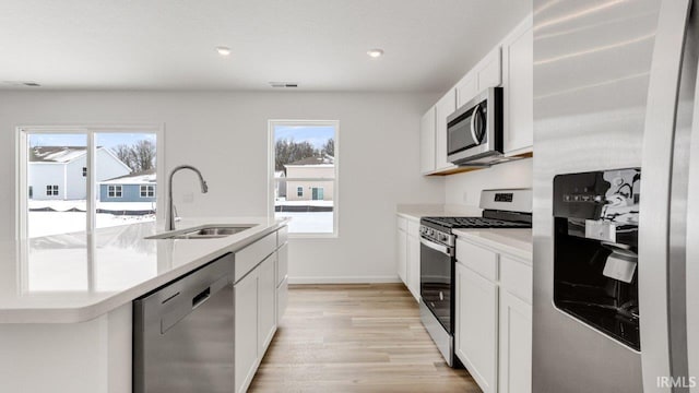 kitchen featuring stainless steel appliances, light countertops, a healthy amount of sunlight, and a sink