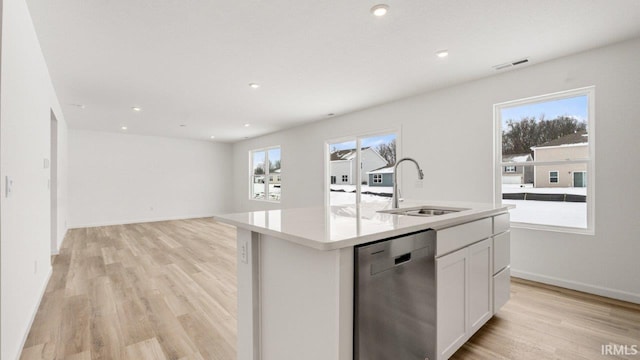 kitchen featuring light wood finished floors, visible vents, white cabinets, stainless steel dishwasher, and a sink