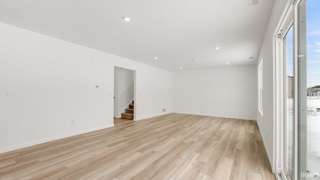 spare room with light wood-type flooring, baseboards, stairway, and recessed lighting