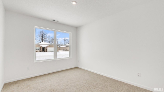 empty room with carpet floors, visible vents, and baseboards