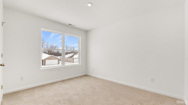 unfurnished room with light carpet, visible vents, and baseboards