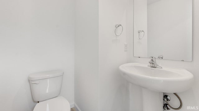 half bath with baseboards and toilet