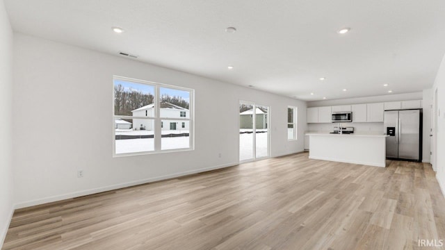 unfurnished living room featuring light wood-style floors, visible vents, baseboards, and recessed lighting