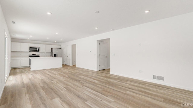 unfurnished living room with light wood-style floors, baseboards, visible vents, and recessed lighting