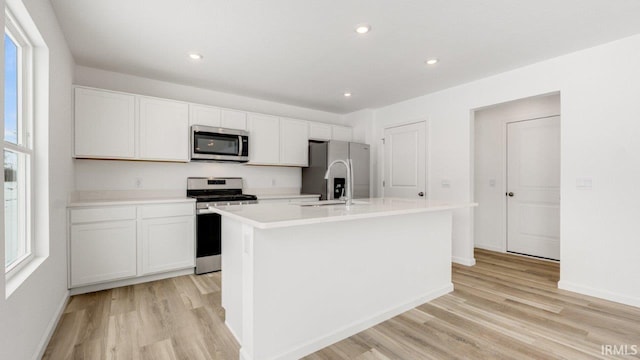 kitchen featuring stainless steel appliances, light wood-type flooring, a kitchen island with sink, and a sink