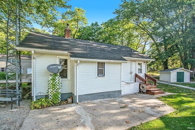 view of front facade featuring a storage shed, a chimney, a patio, and an outdoor structure