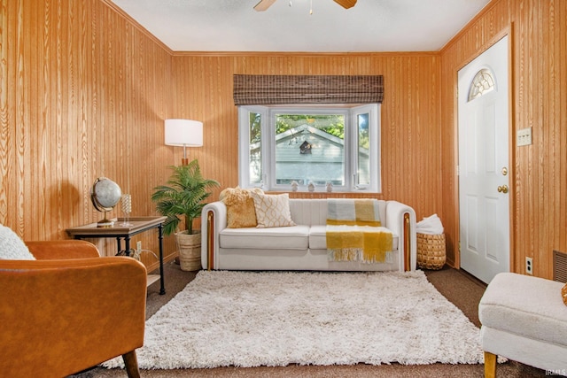 living area featuring carpet, a ceiling fan, and crown molding