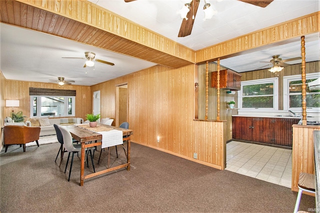 dining room with carpet, wood walls, and tile patterned floors