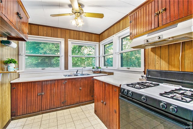 kitchen featuring plenty of natural light, range with gas cooktop, light countertops, under cabinet range hood, and a sink