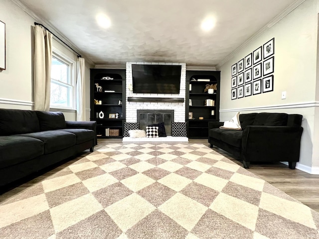 living room featuring built in shelves, a fireplace, ornamental molding, and light wood finished floors