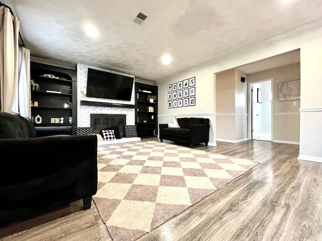 living room featuring ornamental molding, a brick fireplace, wood finished floors, and visible vents