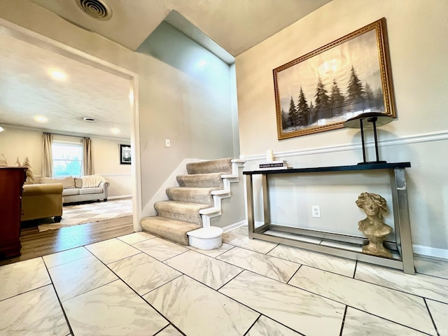 foyer entrance with marble finish floor, baseboards, stairs, and visible vents