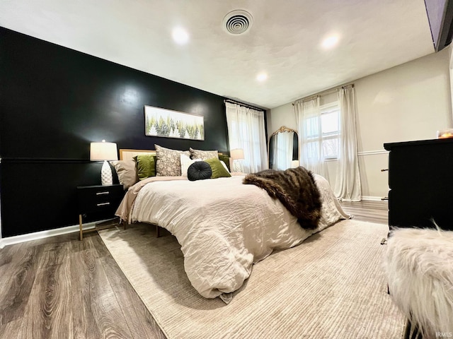 bedroom with visible vents, baseboards, and wood finished floors