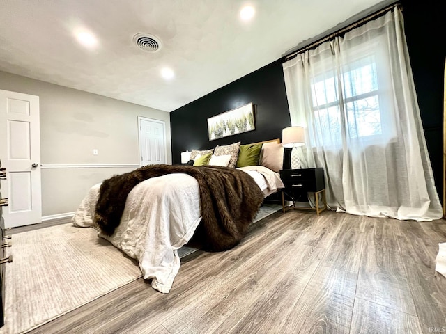 bedroom featuring visible vents, baseboards, and wood finished floors