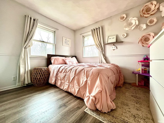 bedroom featuring multiple windows, baseboards, and wood finished floors