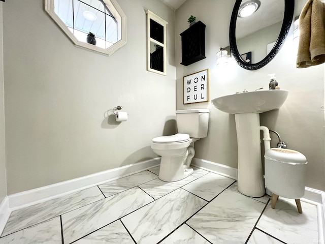 bathroom featuring marble finish floor, baseboards, and toilet