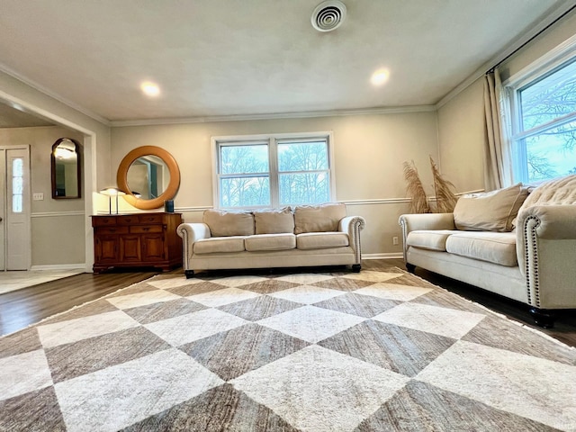 living area with visible vents, crown molding, baseboards, and wood finished floors