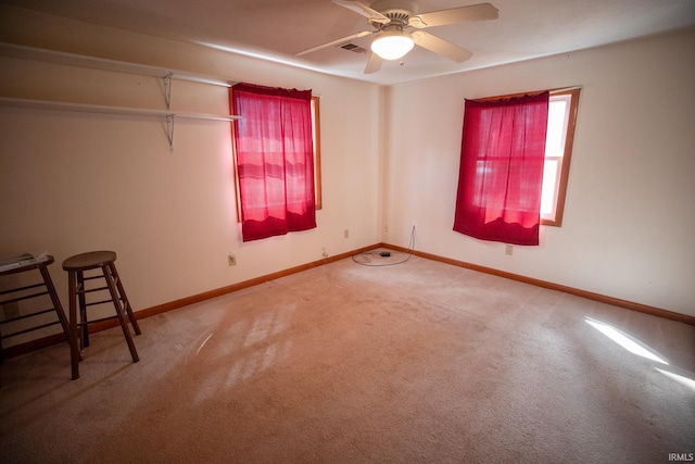 empty room featuring carpet floors, visible vents, ceiling fan, and baseboards