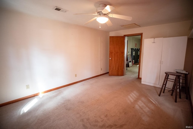 spare room with light carpet, a ceiling fan, visible vents, and baseboards