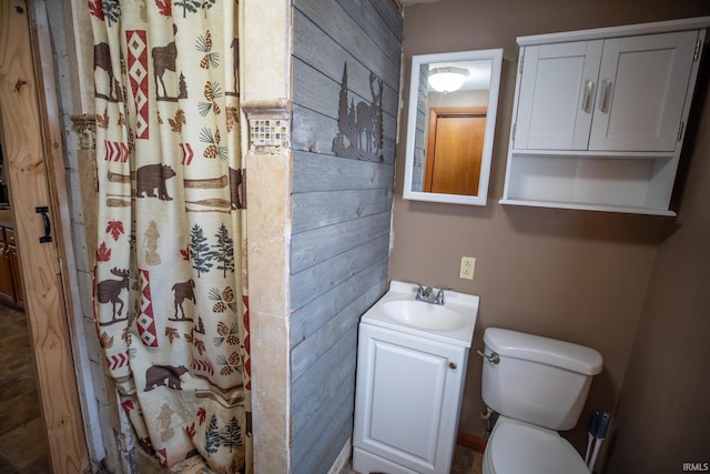 bathroom featuring a shower with curtain, wooden walls, toilet, and vanity