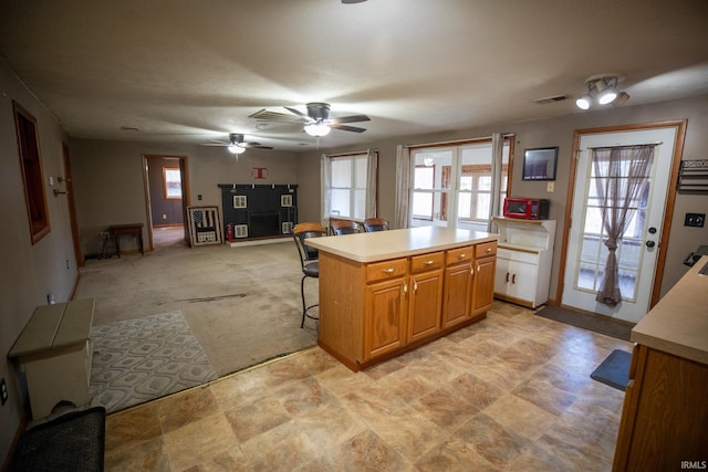 kitchen featuring light countertops, a breakfast bar, a kitchen island, and a wealth of natural light