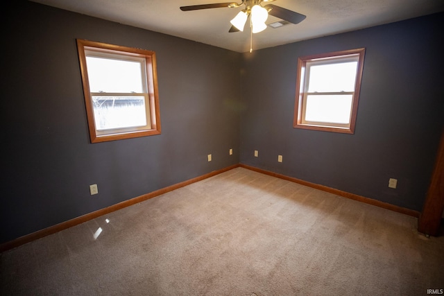 carpeted empty room featuring ceiling fan, a wealth of natural light, and baseboards