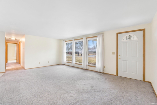 unfurnished living room featuring carpet floors, visible vents, and baseboards